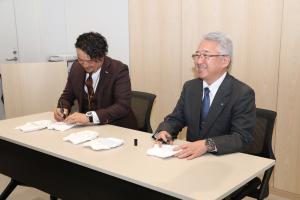 おむつに記名する堀川会長と町長